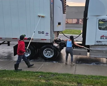 Deux personnes effectuent le lavage extérieur d’un camion et de sa remorque